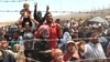 Syrian refugees, flee intense fighting in northern Syria between Kurdish fighters and Islamic State militants, are seen massed at the Turkish border in Akcakale, southeastern Turkey, June 15, 2015.