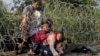 FILE - Syrian migrants cross under a fence into Hungary at the border with Serbia, near Roszke, August 2015.
