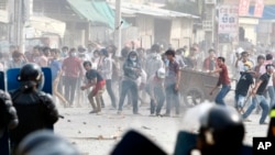 Garment workers throw objects at riot police during a strike near a factory of Canadia Center, on the Stung Meanchey complex at the outskirt of Phnom Penh, Cambodia, Friday, Jan. 3, 2014. Police wounded several striking Cambodian garment workers Friday when they opened fire to break up a labor protest, witnesses said.(AP Photo/Heng Sinith)