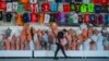 A shop clerk carries mannequins at a soccer jerseys stand at a tourist shopping area, in Belek, Antalya, Turkey, Saturday, March 12, 2022. After losing two years to the COVID-19 pandemic, shopkeepers in the heart of the Turkish Riviera had hoped for a str