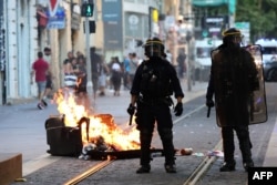 TOPSHOT - French riot police officers stand guard next to a burnt out trash bin during a demonstration against police in Marseille, southern France on July 1, 2023.
