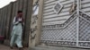 FILE - A man looks at graffiti supporting the Islamic State group as he walks past an entrance of a compound in Karachi, Pakistan, Nov. 12, 2014. Authorities in Pakistan are reported to have arrested five suspected IS operatives in Karachi Monday.
