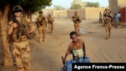French soldiers patrolling the streets of Gao, Mali, walk past a boy carrying canisters on Dec. 4, 2021.