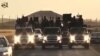 FILE - An image grab taken from a video released by Islamic State group's official Al-Raqqa site via YouTube allegedly shows Islamic State (IS) group recruits riding in armed trucks in an unknown location. 