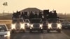 FILE - An image grab taken from a video released by Islamic State group's official Al-Raqqa site via YouTube allegedly shows Islamic State (IS) group recruits riding in armed trucks in an unknown location. 