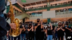 Waandamanaji wakiwa wamefunika nyuso zao wakikiuka katazo la hivi karibuni la kufunika nyuso jengo kubwa lenye maduka ya biashara Hong Kong, Oct.13, 2019.