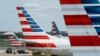 FILE - A member of a ground crew walks past American Airlines planes parked at the gate during the coronavirus disease (COVID-19) outbreak at Ronald Reagan National Airport in Washington, Apr. 5, 2020. 