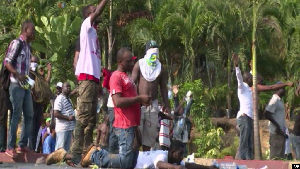Des manifestants assis et couchés par terre, mains levées, font face aux forces de sécurité, à Libreville, 31 août 2016.