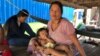 Seum Sreyoun, an unemployed garment worker, sat with her family underneath their home in Pongro village, Kampong Speu province, Cambodia, April 5, 2020. (Sun Narin/VOA Khmer)
