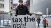 Austrian Marlene Engelhorn, whose family owns Germany's chemical giant BASF, poses with a placard reading "Tax the rich!" at the entrance of the Congress center on the opening of the annual meeting of the World Economic Forum in Davos, on Jan. 15, 2024. 