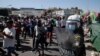 Asylum seekers take part in a rally as riot police block the road near Mytilene town, on the island of Lesbos, Greece, Sept. 11, 2020, after fires destroyed the notoriously overcrowded Moria camp, leaving thousands without shelter.