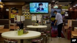 A restaurant employee cleans the floor as a TV screens broadcasting Hong Kong Chief Executive Carrie Lam talks during a press conference in Hong Kong, Friday, July 31, 2020. Hong Kong leader Carrie Lam said Friday that the government will postpone…
