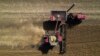 FILE - A combine, bottom, unloads grain into a wagon, top, while harvesting soybeans, Oct. 10, 2023, at a farm near Allerton, Illinois.