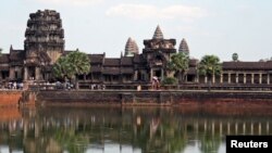 FILE - Tourists walk along the outer wall of Angkor Wat, reflected in its moat in Siem Reap. Russian PM Dmitry Medvedev visited the complex before heading on to Phnom Penh, where he will meet Cambodian leader Hun Sen.