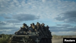 Ukrainian servicemen ride on Armoured Personnel Carrier (APC) in the town of Izium