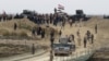 Iraqi security forces gather near a temporary bridge built by the corps of engineers in the Iraqi army south of Ramadi, during a visit by Iraqi Prime Minister Haider al-Abadi on Dec. 29, 2015, after government forces recaptured the city from the Islamic State jihadist group.