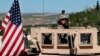 FILE - In this April 4, 2018 file photo, a U.S. soldier sits on his armored vehicle on a road leading to the front line in Manbij, Syria.