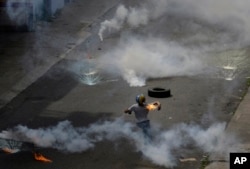 Un manifestante lanza una bomba molotov a la policía que lanzó gases lacrimógenos a una protesta de médicos y estudiantes de medicina que exigían la apertura de un canal humanitario en Caracas.