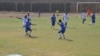 Les équipes d'Athleta FC (blanc) et le club "les amis du monde" (bleu) se rencontrent à Lomé, au Togo, le 18 mars 2017. (VOA/Kayi Lawson)