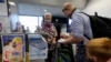 In this Oct. 15, 2020 file photo, a United Airlines agent checks in passengers at the gate to board a flight to Hawaii at San Francisco International Airport in San Francisco.(AP Photo/Jeff Chiu, File)