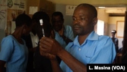 A medical worker at Likuni Community Hospital, in Lilongwe, Malawai draws the malaria vaccine into a syringe for vaccination.