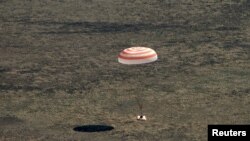 La cápsula Soyuz con tres astronautas a bordo desciende con ayuda de un paracaídas en las estepas de Kazijistán el 17 de abril de 2020.