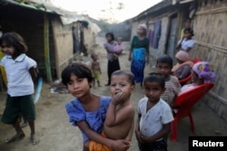 A Rohingya refugee girl carries a baby inside a refugee camp in Sitwe, in the state of Rakhine, Myanmar, March 4, 2017.