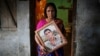 Fatema holds a picture of her son Nurul Karim as she poses for a photograph in front of her house in Savar, April 21, 2014. Fatema lost her son and her daugther Arifa, who were working at the Rana Plaza when it collapsed on April 24, 2013.