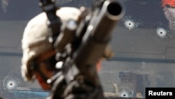 FILE - A U.S. Army soldier is seen in front of a bullet-riddled truck in the Pesh Valley in Afghanistan's Kunar Province, Aug 4, 2009. The U.S. military is investigating a video that appears to show an American service member firing into the cab of a civilian truck in Afghanistan.