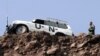 FILE - An official from the U.N. Military Observers Group in India and Pakistan walks toward his vehicle on the Pakistan-administered Kashmir side at Kaman Post, 118 km (73 miles) west of Srinagar, Feb. 11, 2006. 