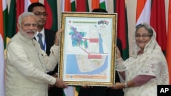 Bangladesh’s Prime Minister Sheikh Hasina, right, and Indian Prime Minister Narendra Modi hold a location map of Indian Economic Zones during an agreement program in Dhaka, Bangladesh, June 6, 2015.