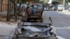 Men rest at the back of a pickup truck near a damaged car in the rebel held al-Katerji district in Aleppo, Syria, Aug. 13, 2016. 