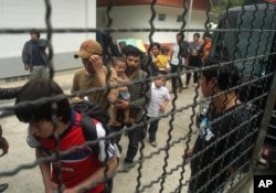 FILE - Ethnic Uighur Muslims line up beside a police van in Khlong Hoi Khong of southern Songkhla province, Thailand, March 15, 2014.