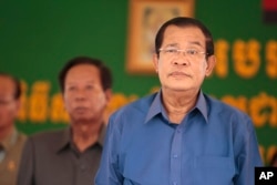 FILE - Cambodia's Prime Minister Hun Sen, right, prepares to deliver a speech during a factory visit outside of Phnom Penh, Cambodia, Aug. 30, 2017.