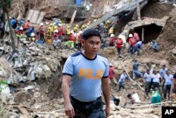 In this Sept. 18, 2018 photo, Philippine Police Senior Inspector Heherson Zambale walks at the site where victims are believed to be buried in a landslide set off by Typhoon Mangkhut as it lashed across Itogon, Benguet province, northern Philippines.