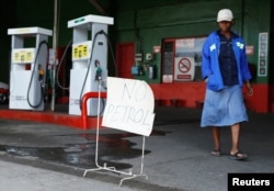 A woman walks past a "No Petrol" sign at a fuel station in Harare, Zimbabwe, Oct. 9, 2018.