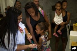 Tais da Silva Almeida comforts her 5-year-old daughter as a health worker prepares to inject her with a yellow fever vaccine in a field hospital in Casimiro de Abreu, Brazil, March 17, 2017.