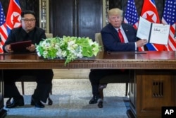 FILE - U.S. President Donald Trump holds up document that he and North Korea leader Kim Jong Un signed at their summit on Sentosa Island, June 12, 2018, in Singapore.