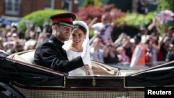 Prince Harry and his wife, Meghan Markle, wave as they ride a horse-drawn carriage after their wedding ceremony at St George's Chapel in Windsor, Britain, May 19, 2018. 