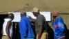 People look at results placed outside a polling station in Harare, Zimbabwe, July 31, 2018. 