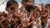 FILE - Syrian refugee children wave and flash the V-sign at a refugee camp in Suruc, on the Turkey-Syria border, June 19, 2015.