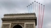 France's national colors trail above the Arc de Triomphe during the traditional Bastille Day parade on the Champs Elysees in Paris, July 14, 2014.