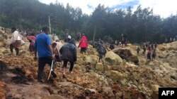 Residents walk on top of a landslide at Yambali, Papua New Guinea, on May 25, 2024. (International Organization for Migration via AFP)