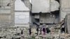 Children walk on the debris of a damaged building at al-Myassar neighborhood of Aleppo, Syria, Feb. 16, 2015.