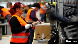 Employees handle packages in the new Amazon logistics center in Dortmund, Germany, Nov. 14, 2017.
