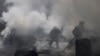 FILE - Civil defense members try to put out a fire at a site hit by what activists said was a barrel bomb dropped by forces loyal to Syria's President Bashar al-Assad in the Qadi Askar neighborhood of Aleppo, March 5, 2015. 
