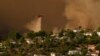 Un hélicoptère largue de l'eau sur les maisons alors que l'incendie de Palisades progresse dans le Mandeville Canyon, le samedi 11 janvier 2025, à Los Angeles.