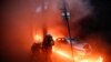Des pompiers à côté d'une voiture entourée de flammes lors d'une manifestation contre un projet de loi controversé, à Paris, France, le 5 décembre 2020. 