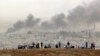 People on a hilltop watch smoke rising from a fire caused by a strike in Kobani, Syria, during fighting between Syrian Kurds and the militants of Islamic State group, on the outskirts of Suruc, at the Turkey-Syria border, Oct. 11, 2014.