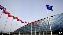 FILE - Flags of NATO alliance members flap in the wind outside NATO headquarters in Brussels, Feb. 28, 2020.